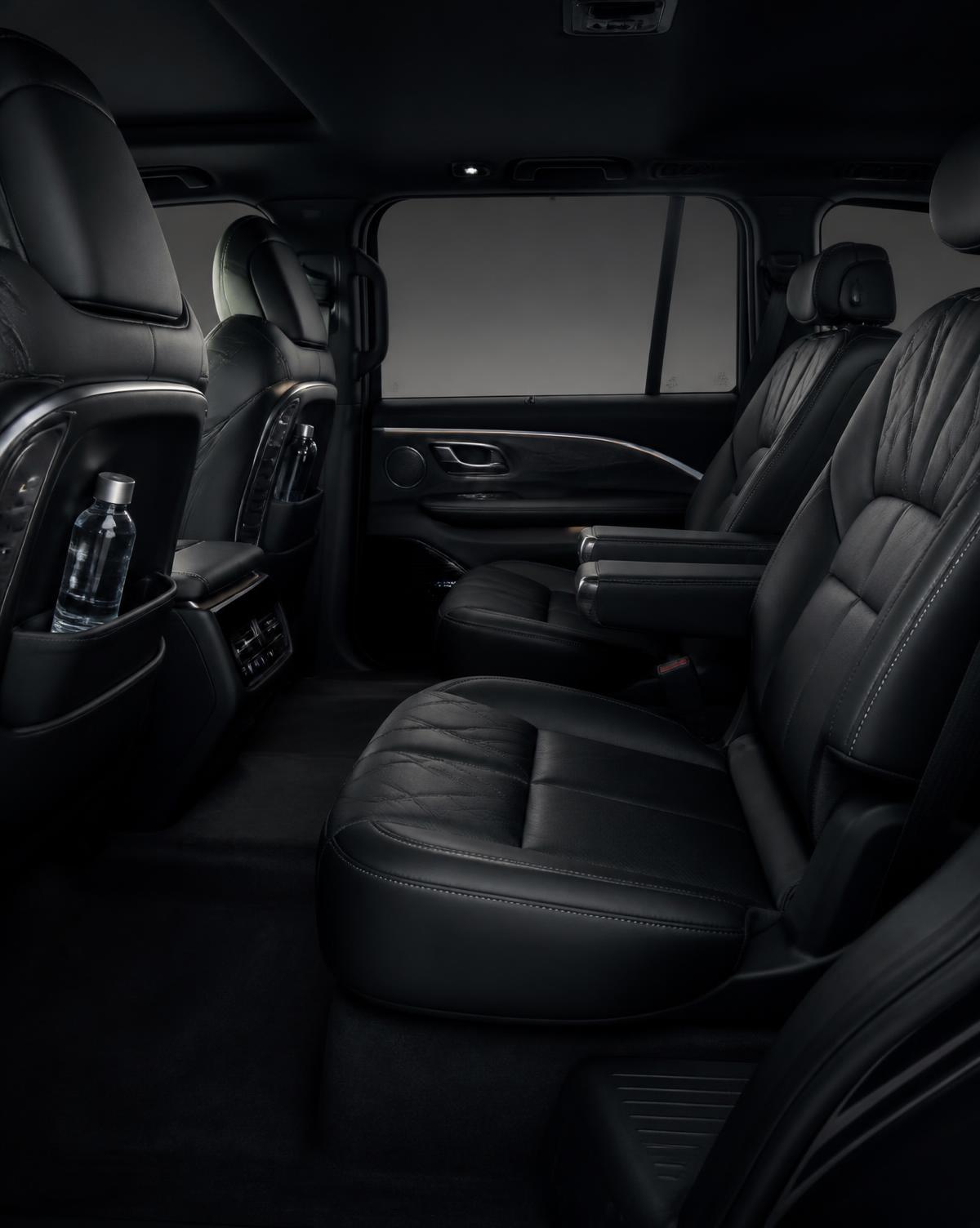 Second-row leather seating and bottled water inside the black luxury SUV cabin